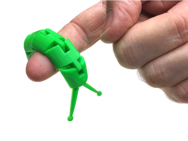 an articulated, printed slug hanging over a person's finger